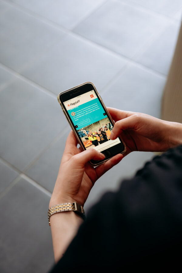 Hands holding a phone. Website on phone screen.