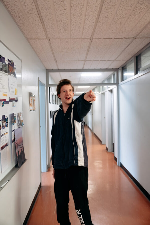 Participant standing in the hallway, pointing.