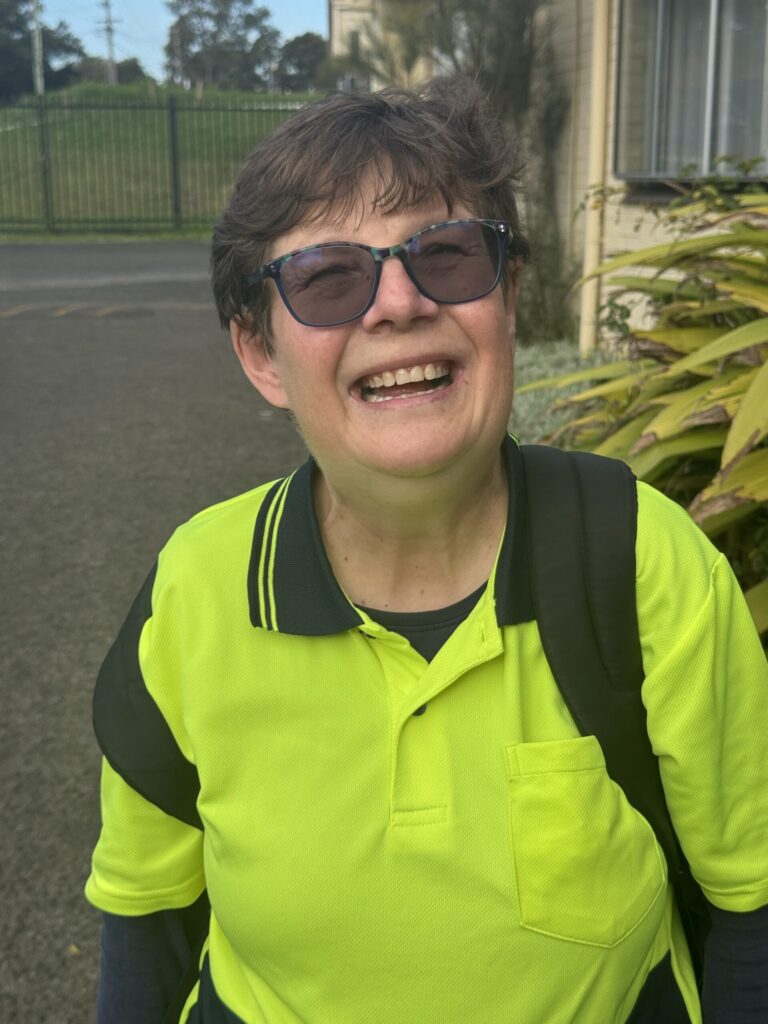Rachel smiling. Outside. Yellow shirt.