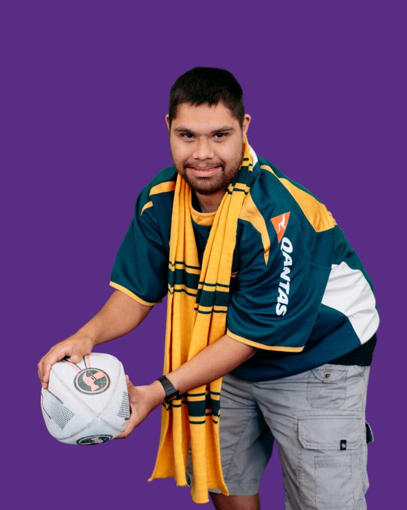 Tel mid toss of a white football. Looking straight forward. Green jersey and yellow scarf.